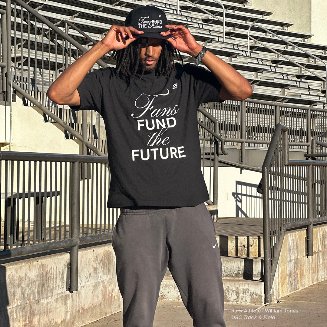Person wearing a black t-shirt with 'Fans Fund the Future' text, standing in an outdoor setting.